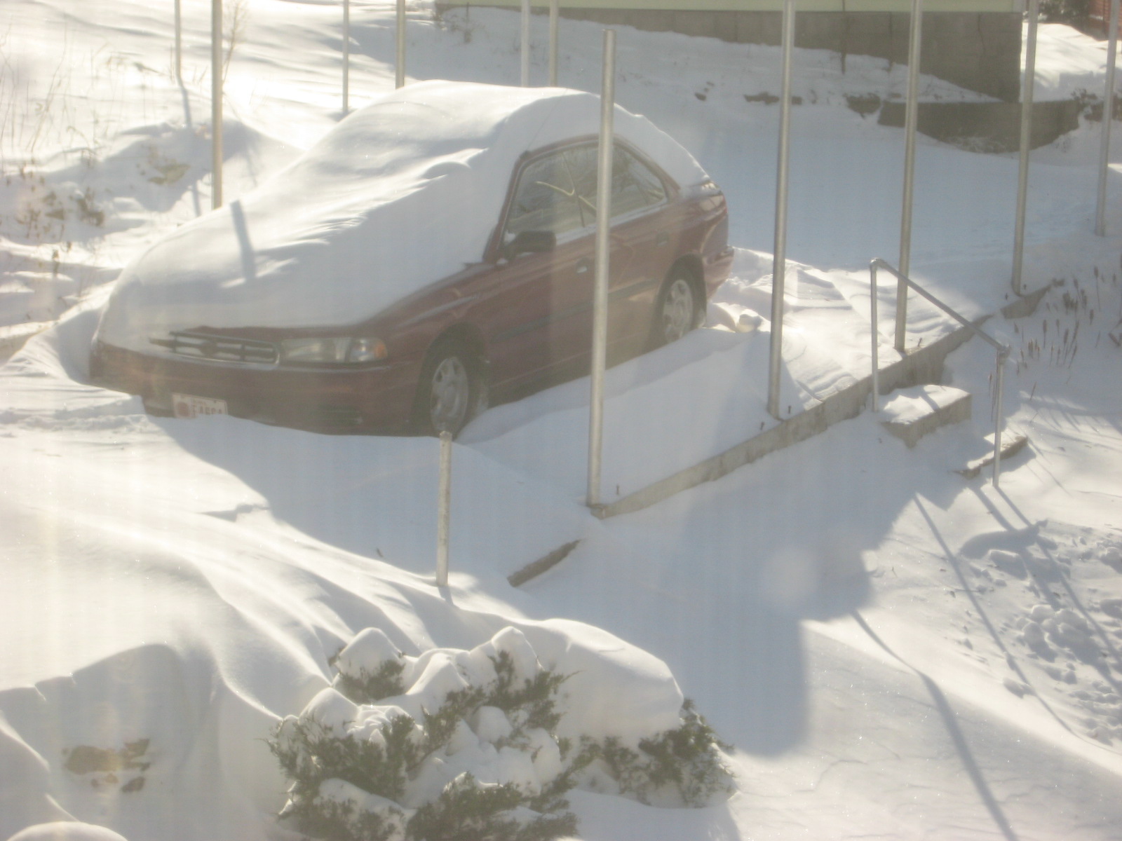 Downward view of a red car buried in deep snow