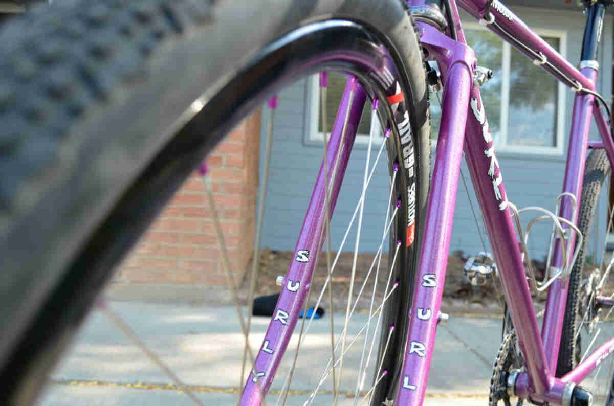 Cropped, lower, front left side view of a purple Surly Straggler bike