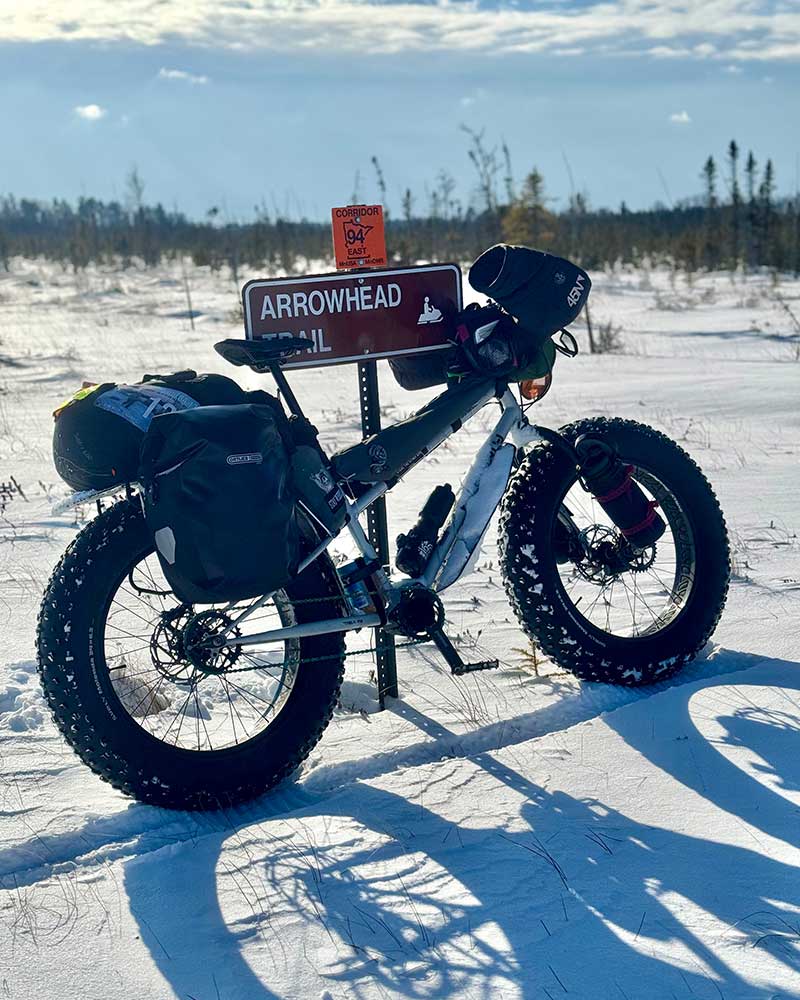 Surly Moonlander fat bike fully loaded leaning against Arrowhead Trail sign