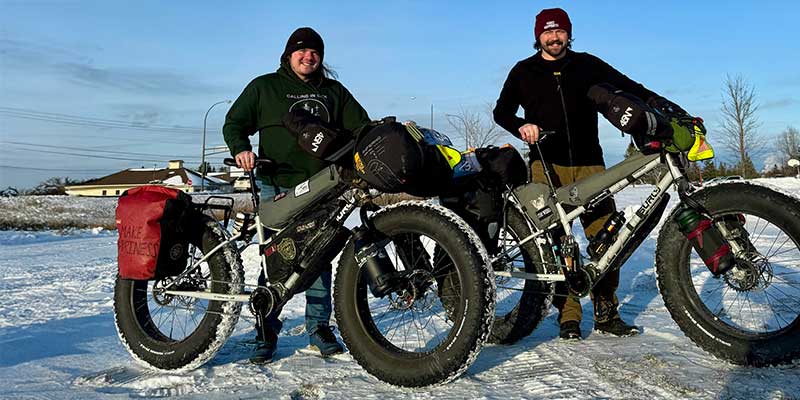 Price brothers together standing behind their fully-loaded Surly Moonlander fat bikes smiling