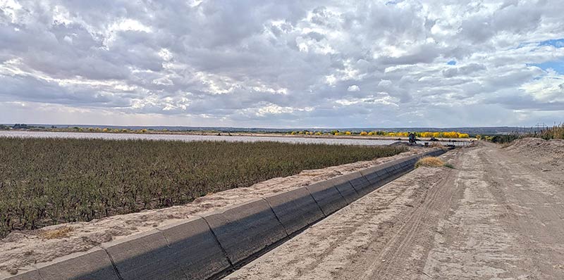 Gravel construction road with concrete irrigation channel on side