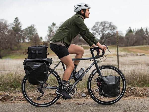 Cyclist riding Surly Disc Trucker on rural road loaded with pannier bags for touring