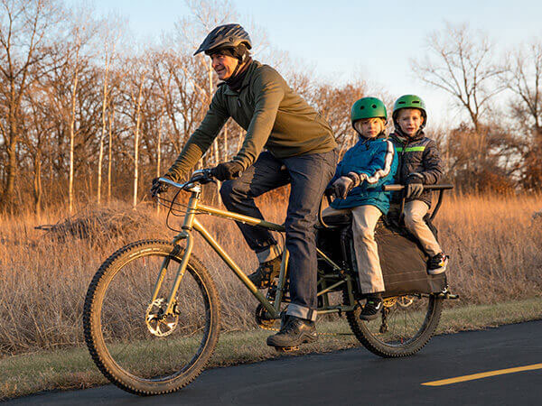 Cyclist riding Surly Big Fat Dummy with two children on back