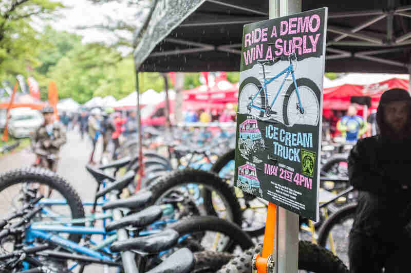 A, Ride a Demo, Win a Surly sign, posted on a canopy leg, with a row of bikes  and canopies in the background 