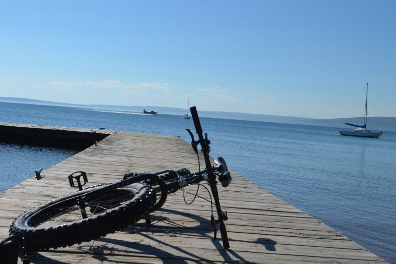 Front view of a Surly bike, on a wood dock, laying on it's left side, with Madeline Island in the background