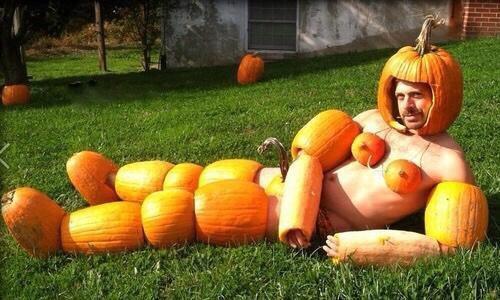 A person, laying on grass, wearing an outfit made of a pumpkins