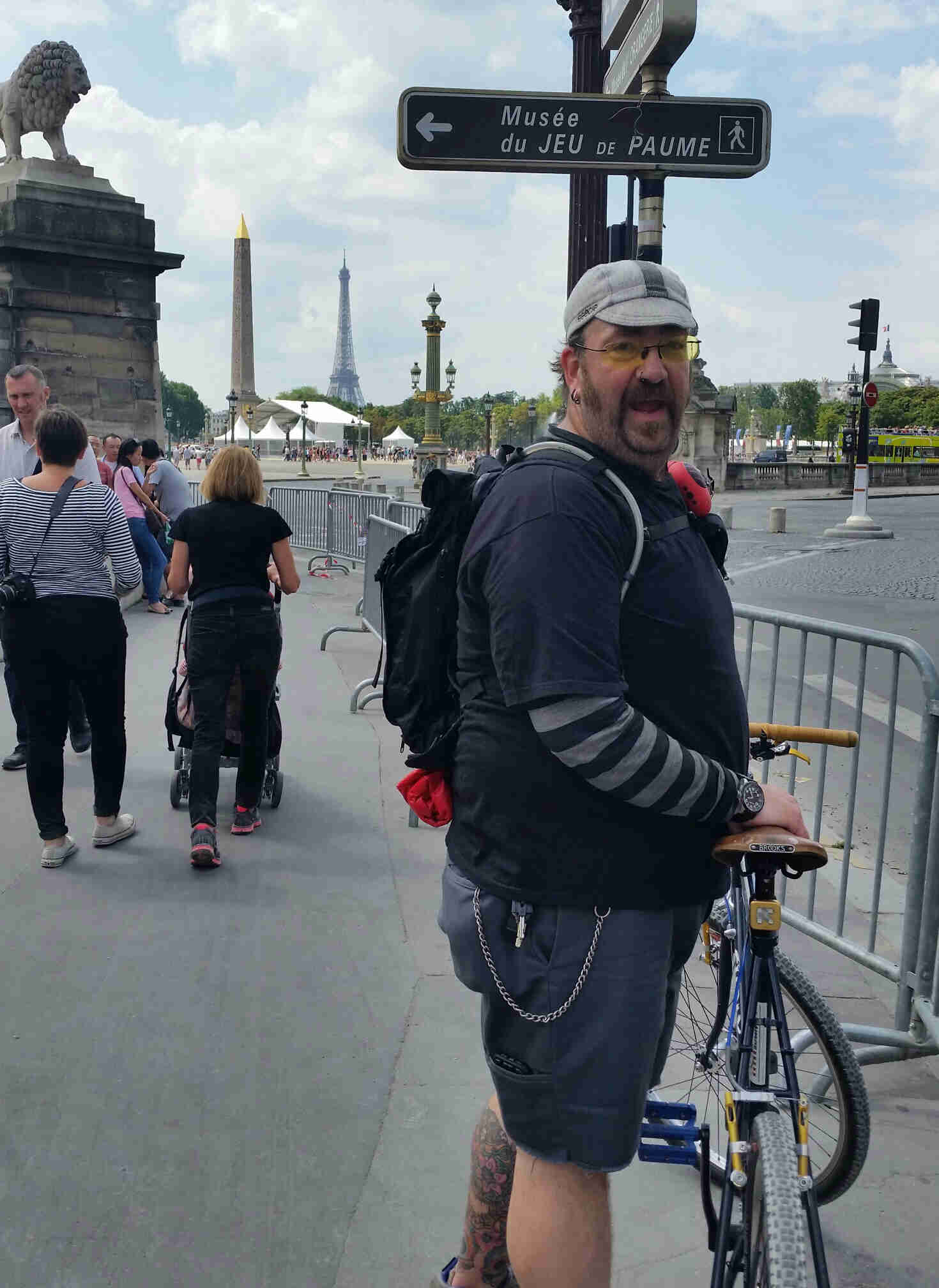 Rear, right side view of a Surly bike with cyclist standing on left side, on a sidewalk, with Eiffel tower behind them