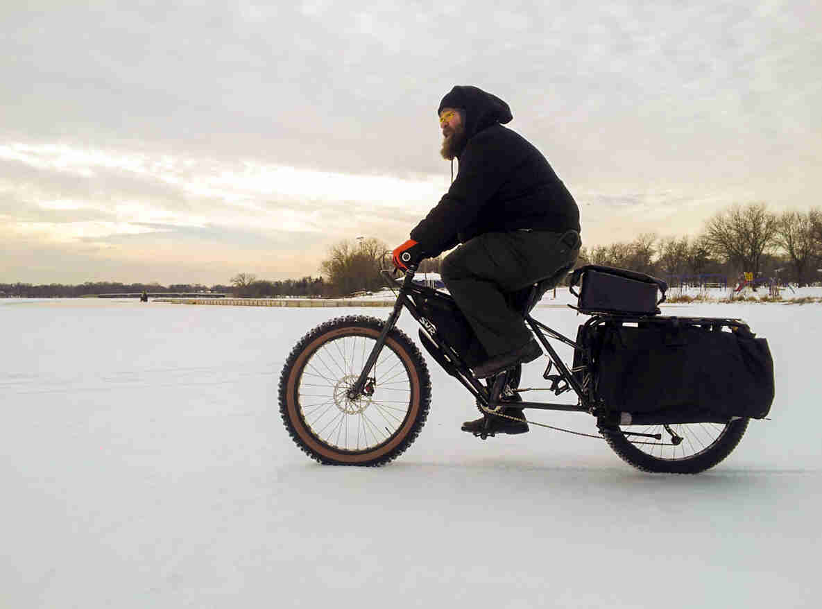 Left side view of a cyclist riding Surly Big Fat Dummy bike on a frozen lake