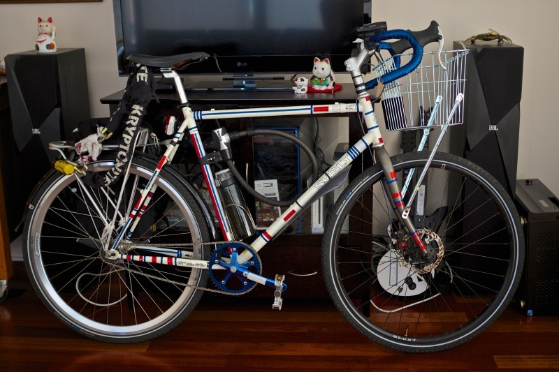 Right side view of a Surly bike, covered in red and white stripes, parked against a stand with a TV on top, in a room