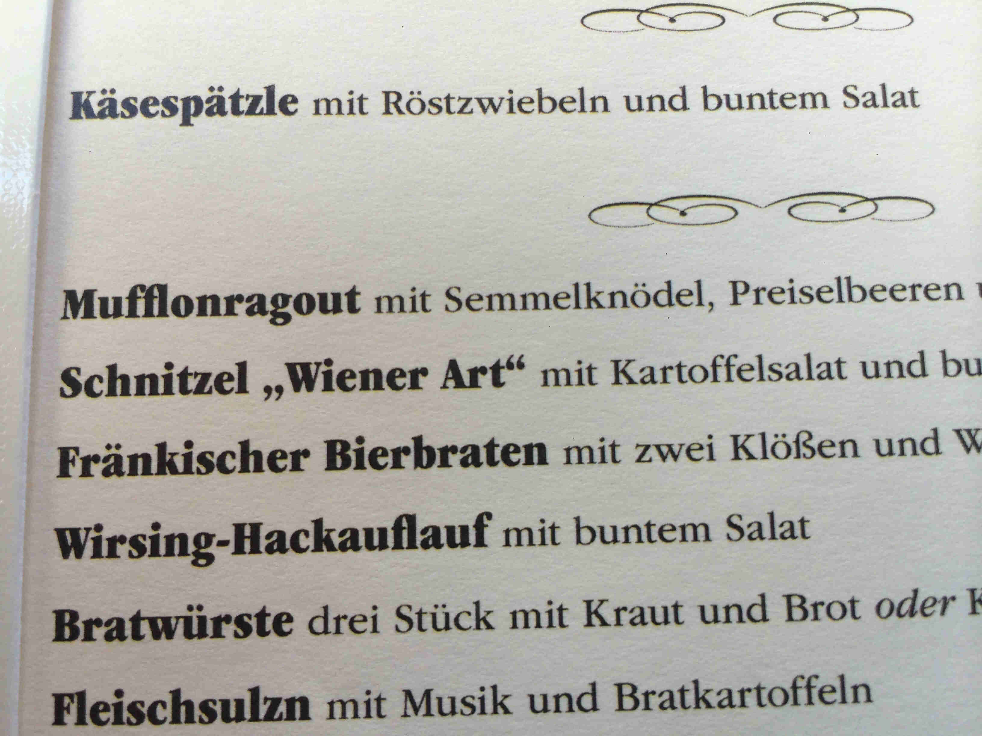 Close up view of a German food menu, on white paper with black text