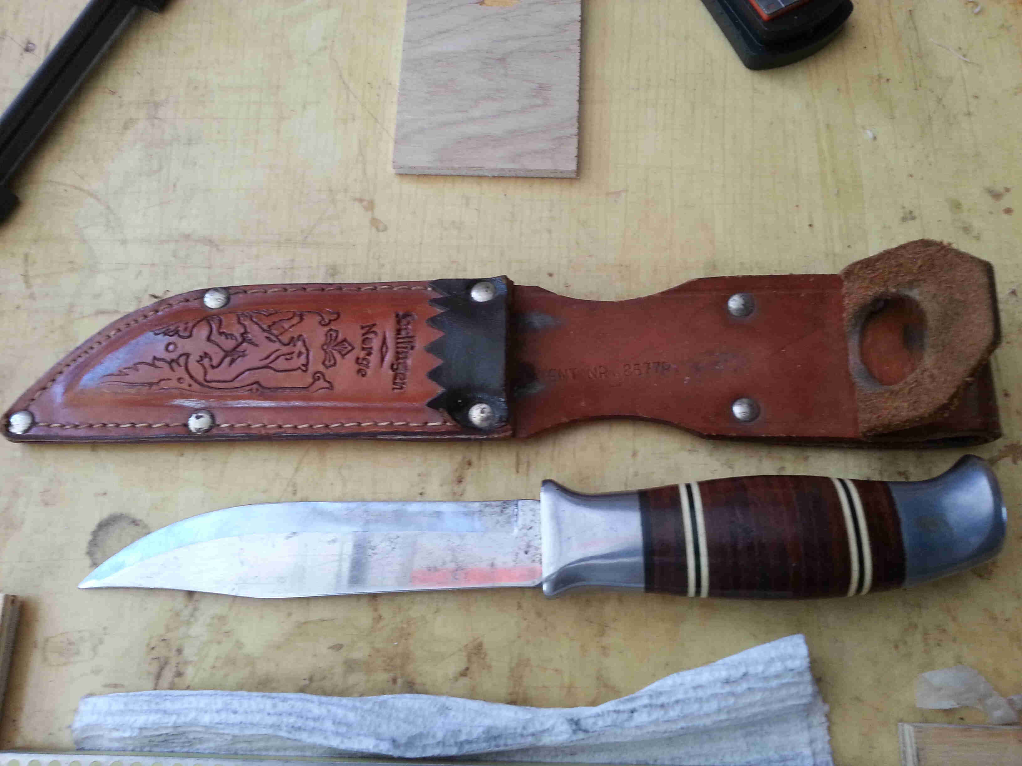 Downward view of a leather sheath, a knife and a white cloth