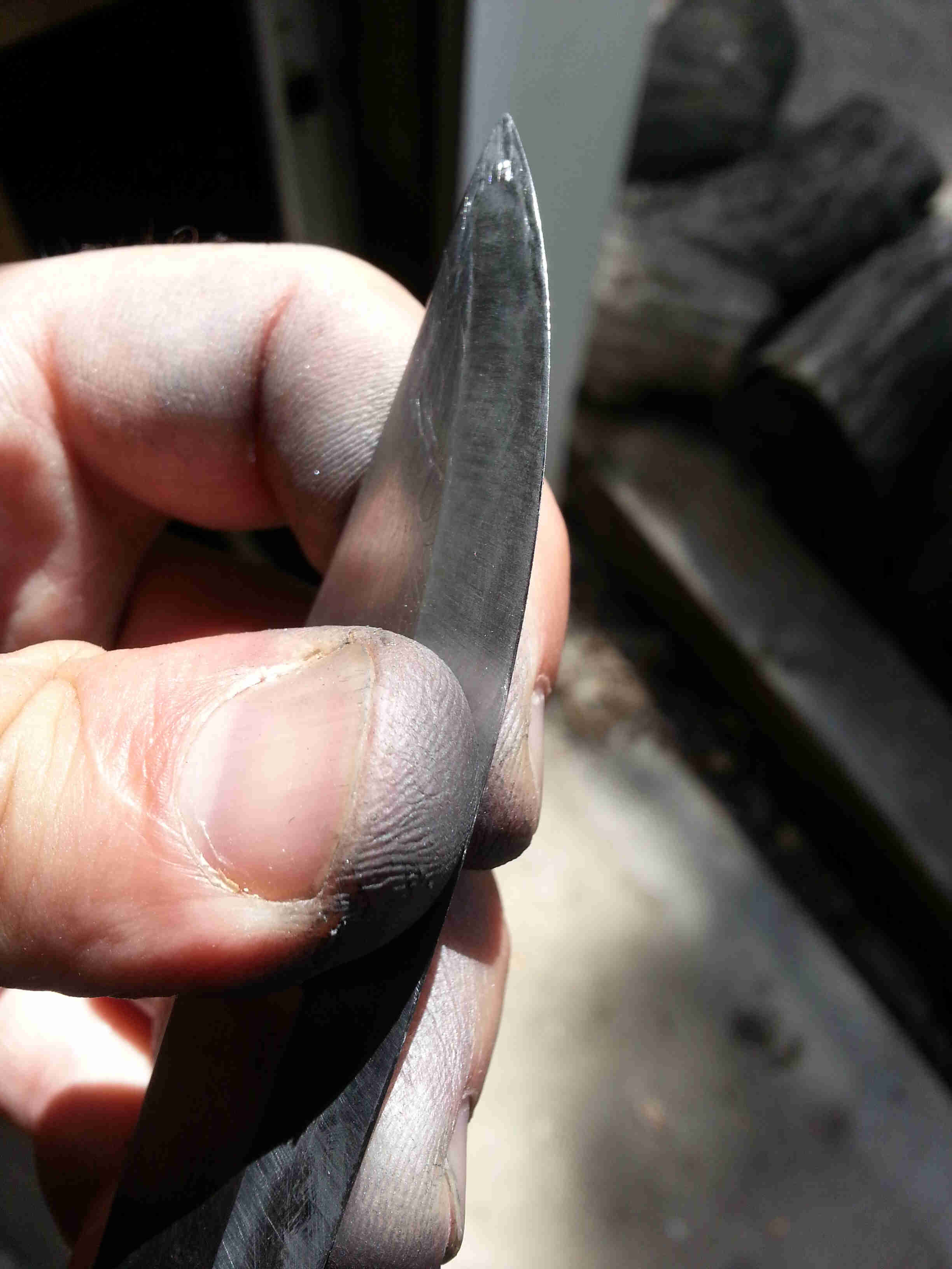 Close up view of fingers holding the end of a knife blade from the flat sides